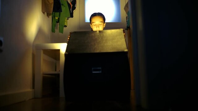 Ni&ntilde;a abriendo caja sorpresa en la penumbra del cuarto trastero