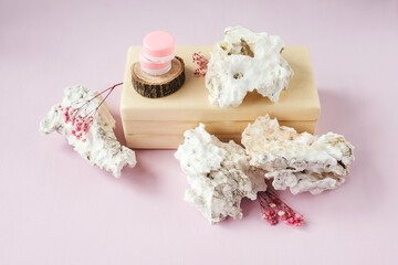Blank cream jars on wooden brick, white stones around. Natural organic cosmetics, sustainable lifestyle concept. Top view, copy space. Pink background and dried flowers.