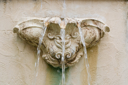 Water flowing from an ornate water fountain in a wall