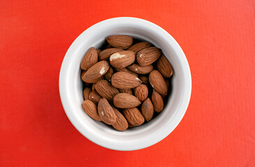 Overhead shot of a pot of raw almonds on a colorful orange background