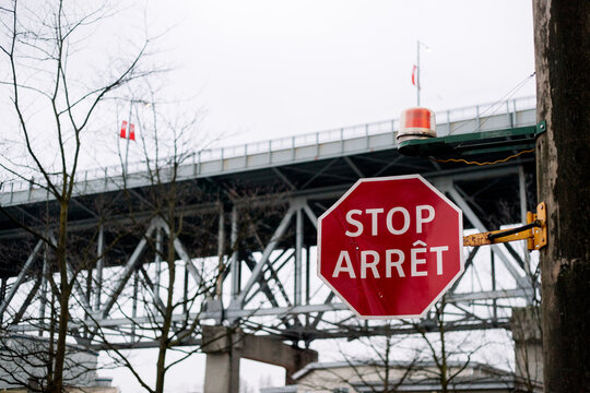 A slightly damaged multi-language stop sign on a lamp post