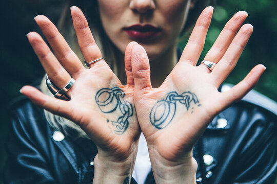 Womans tattooed hands showing broken handcuffs