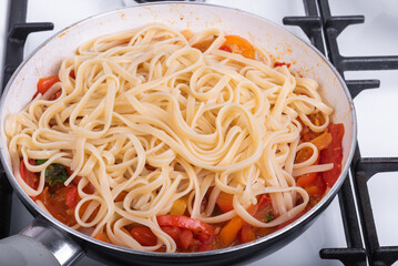Cooking pasta with pepper and tomato sauce for pasta in a frying pan, linguine with bell pepper and tomatoes - close-up