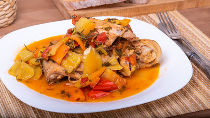 Chicken with bell peppers in a plate on a napkin, macro - a classic Italian recipe, close-up