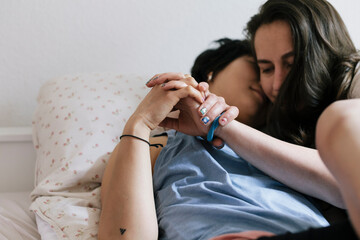 Loving lesbian couple holding hands in bed
