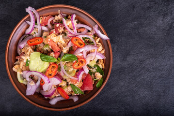 Italian tuscan vegetarian panzanella salad, mixed salad of breads, tomatoes and vegetables in a clay bowl on a black stone surface, top view, copy space