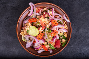 Italian tuscan vegetarian panzanella salad, mixed salad of bread, tomato and vegetables in a clay bowl on a black stone surface, top view, close-up