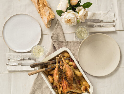 Vintage festive table for two with roast chicken, vegetables and baguette bread
