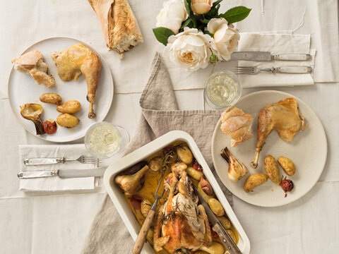 Vintage festive table for two with roast chicken, vegetables and baguette bread
