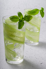 selective focus, refreshing drink with sliced cucumber, in a tall glass with green Basil leaves