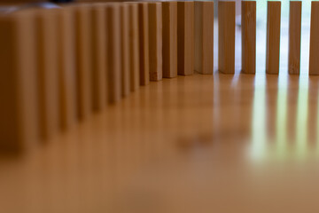 Wooden block domino standing stable on wood table, business chain and connection symbol, domino effect theory