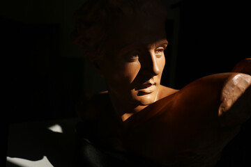 Ritratto di giovane uomo, primo piano di testa in terracotta di provenienza europea, scultura su fondo scuro con spazio per testo 