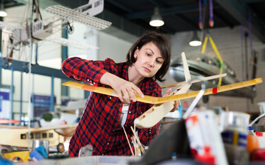 Young woman enjoying her hobby - creating light airplanes in aircraft hangar