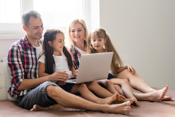 Fototapeta premium Family lying in bed using a laptop