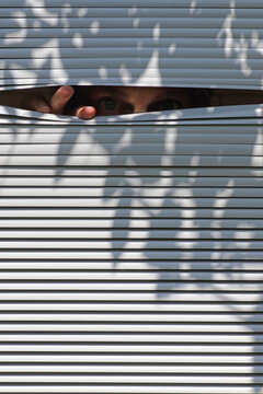man peeping through the blinds