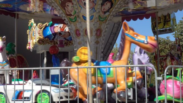Rotating empty children's carousel with colorful animal figurines in 4K. Summer amusement park