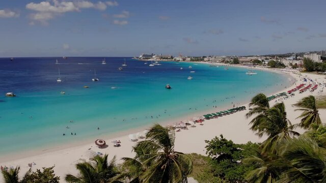 Aerial of the beautiful beach in Barbados. Drone flying dolly over palm trees, beach blue water and boats 