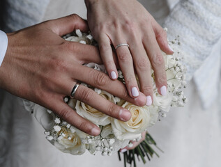 bride's hand with an elegant wedding ring with white gold diamonds on a bouquet of their peonies