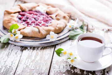 Freshly homemade baked deliciouse strawberry pie with cup of tea on a wooden background. Copy space.
