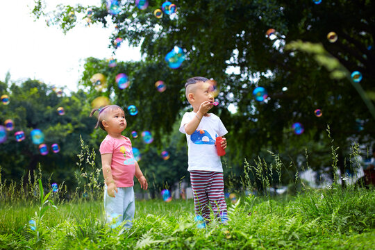two lovely asian kids playing bubble outdoor in the summer park