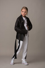 Beautiful little girl child in a leather jacket posing in the studio