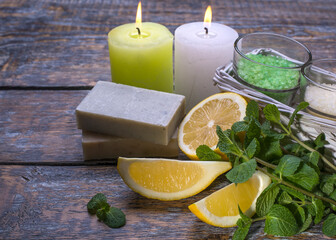 Spa still life with candles and natural soap and lemon fruits on a wooden background, copy space.