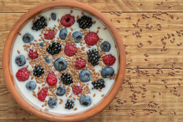 Yogurt with blueberries, raspberries, blackberries, flax seeds in a clay bowl. Served vegetarian dish. Healthy breakfast, healthy food. Background for the menu of restaurants, cafes.