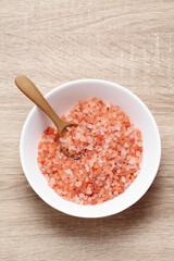 Himalayan pink salt in ceramic cup on wooden table