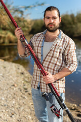 Adult man standing outdoors with angling rod planning to fishing. High quality photo
