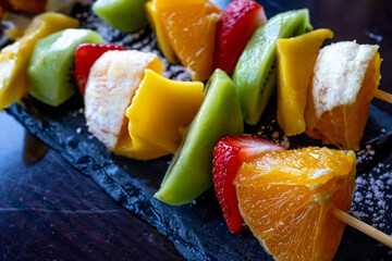 Fruit Kebab made of Oranges, Strawberries, Kiwi, Mango. Macro close-up. Selective focus