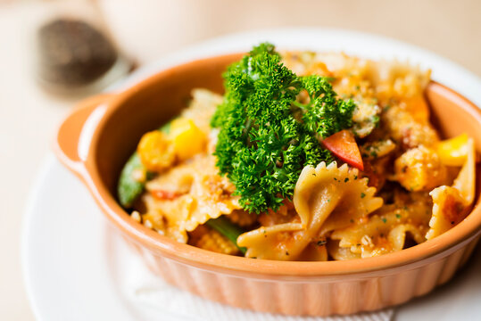 Delicious farfalle pasta in orange plate on table