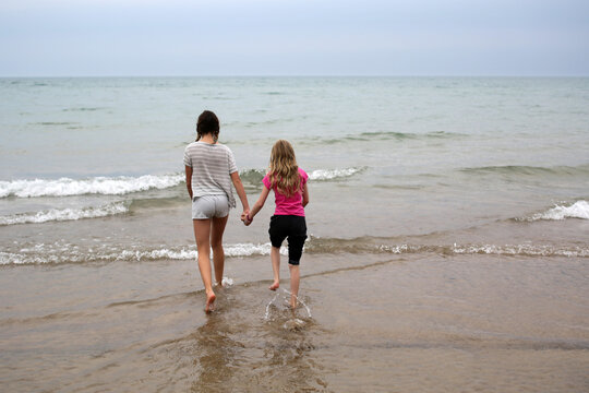 Girlfriends Holding Hands As They Play On The Beach