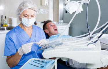 Female dentist with male patient in modern dentistry.