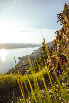 male hiking friends walking up a mountain at sunset with beautiful seasscape