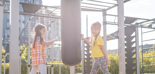 Two cute little girls having fun on a playground outdoors in summer. Sport activities for kids.