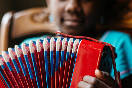 African American girl playing a red and blue accordeon