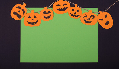 Halloween card with hunging pumpkins on a green black baclground.