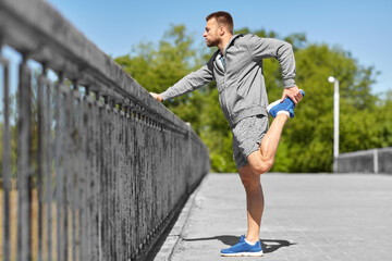 fitness, sport and healthy lifestyle concept - man stretching leg on bridge