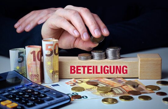 Beteiligung. Hand baut Geldstapel auf einem Baustein mit Text. Turm aus Euro M&uuml;nzen. Taschenrechner daneben.