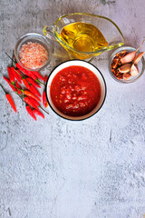 Adjika, hot harissa sauce - spicy hot paste of chilli pepper, tomato on table. Small bowl of homemade harissa with red chili. Copy spase