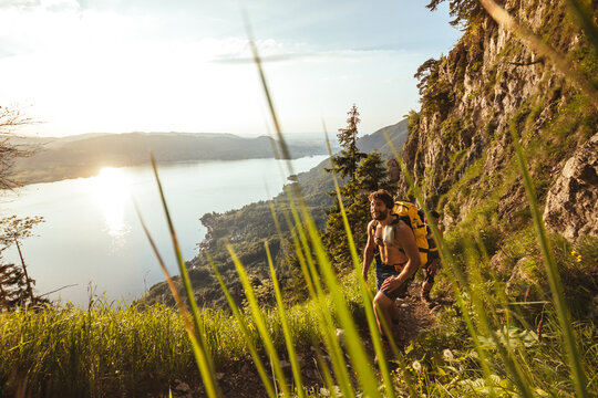 male hiker walking up a mountain with beautiful seascape in the back