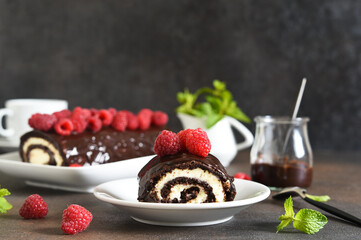 Chocolate roll with cream cheese and raspberries, with a cup of coffee on a dark background.