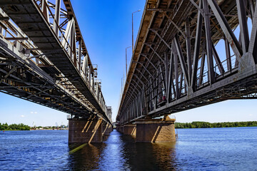 View of the Dnieper river under the Amur bridge in Dnipro (Ukraine). Engineering-architecture geometric background with straight lines and perspective. Water surface with copy space