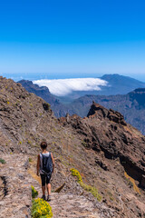 A young woman walking along the path of the Roque de los Muchachos at the top of the Caldera de Taburiente, La Palma, Canary Islands. Spain