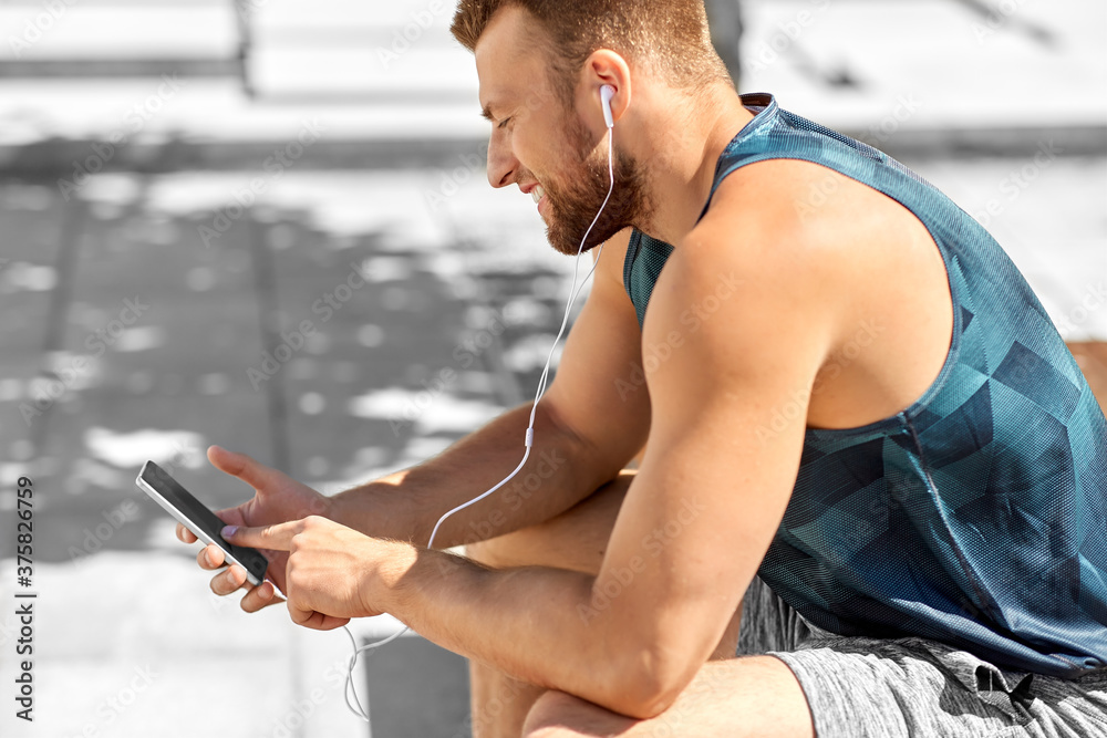 Poster fitness, sport and technology concept - young athlete man with earphones and smartphone listening to