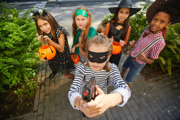 Group of children in Halloween costumes playing trick or treat during holiday they standing outdoors and smiling at camera