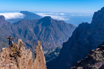 A young man after finishing the trek at the top of the volcano of Caldera de Taburiente near Roque de los Muchachos looking at the incredible landscape, La Palma, Canary Islands. Spain
