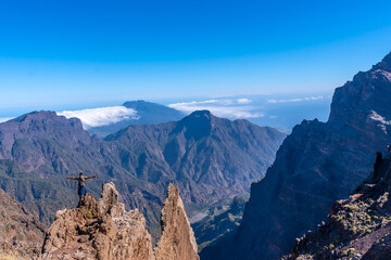 A young man after finishing the trek at the top of the volcano of Caldera de Taburiente near Roque de los Muchachos looking at the incredible landscape, La Palma, Canary Islands. Spain