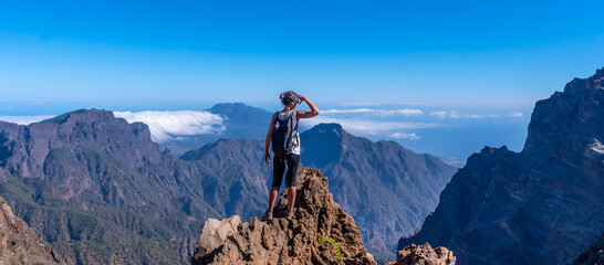 A young woman looking out from the top of the Caldera de Taburiente volcano near Roque de los Muchachos one summer afternoon, La Palma, Canary Islands. Spain