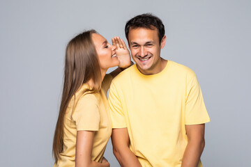 Fototapeta premium Secret and people concept. Happy couple whispering over grey background